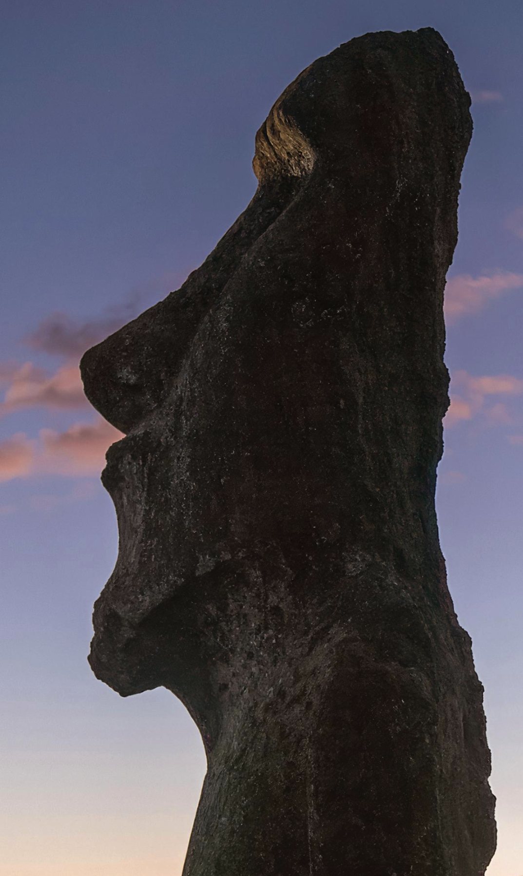 A moai statue silhouetted against a sunset sky on Easter Island, Chile